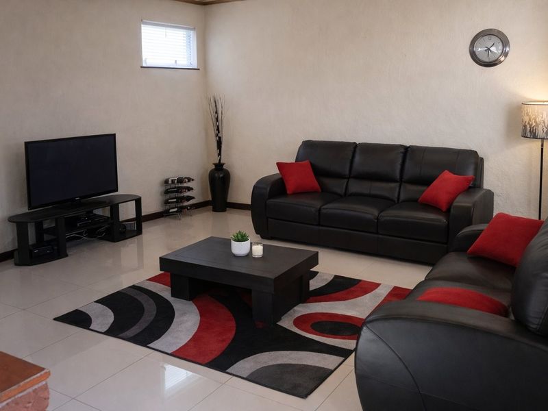 A living room featuring neutral walls, polished tiled flooring, and a small high-level window, providing a functional and well-lit space.
