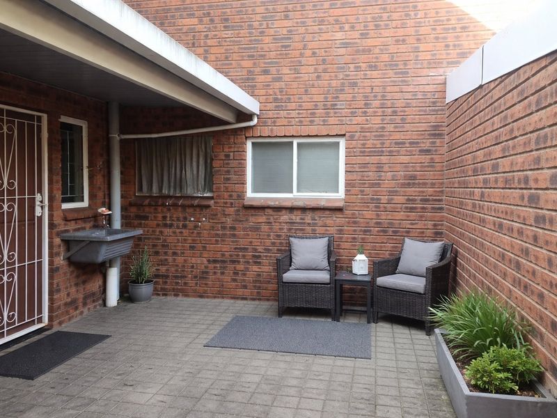 A private paved courtyard area featuring exposed brick walls, a built-in utility sink, and a secure entrance gate.