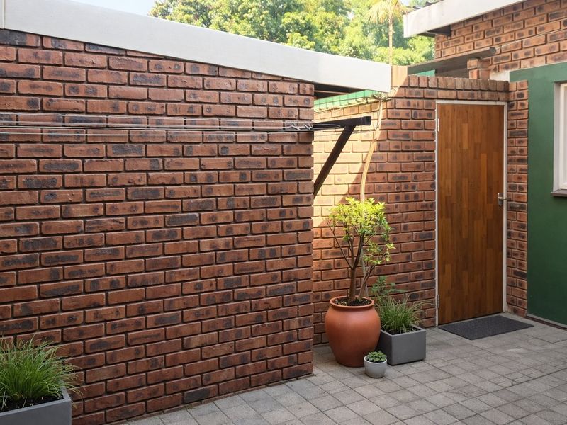 A private rear courtyard featuring face brick walls, paved flooring, and a wall-mounted clothesline, providing a functional outdoor utility space.