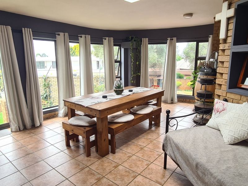 Spacious open-plan living and dining area featuring exposed brick walls, tiled flooring, and large glass doors providing ample natural light and garden access.