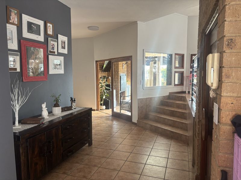Entrance hall featuring tiled flooring, a brick feature wall, and a staircase leading to an elevated level with access to an outdoor patio area.
