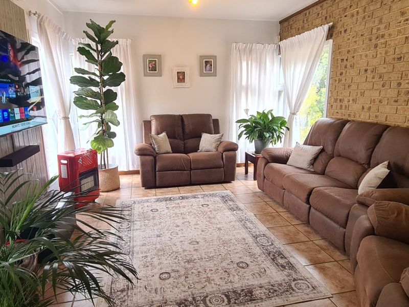 A cozy living room featuring exposed brick walls, tiled flooring, and large windows that provide ample natural light.