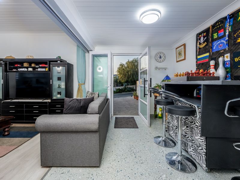A living area featuring terrazzo flooring, tongue and groove ceiling, and direct access to the exterior through a glass panelled door.