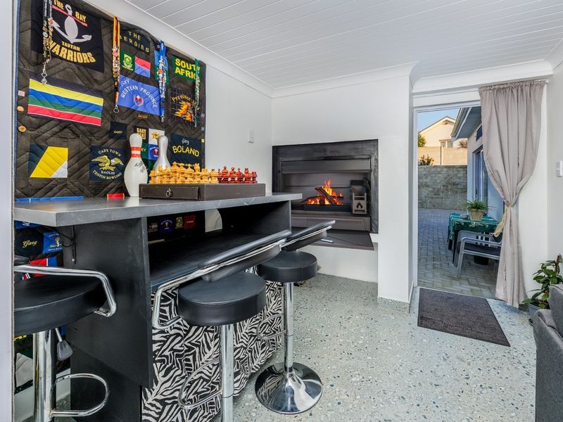 An enclosed patio area featuring a built-in fireplace, a custom bar counter, and durable terrazzo flooring, with direct access to the rear outdoor space.