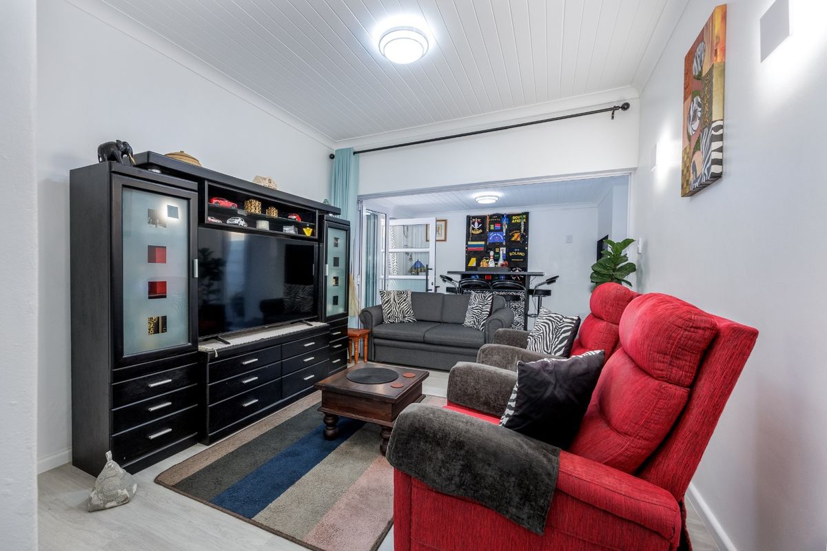 A comfortable living room featuring laminate flooring and a classic tongue and groove ceiling, providing a functional and well-maintained space for relaxation.