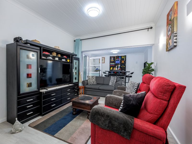 A comfortable living room featuring laminate flooring and a classic tongue and groove ceiling, providing a functional and well-maintained space for relaxation.