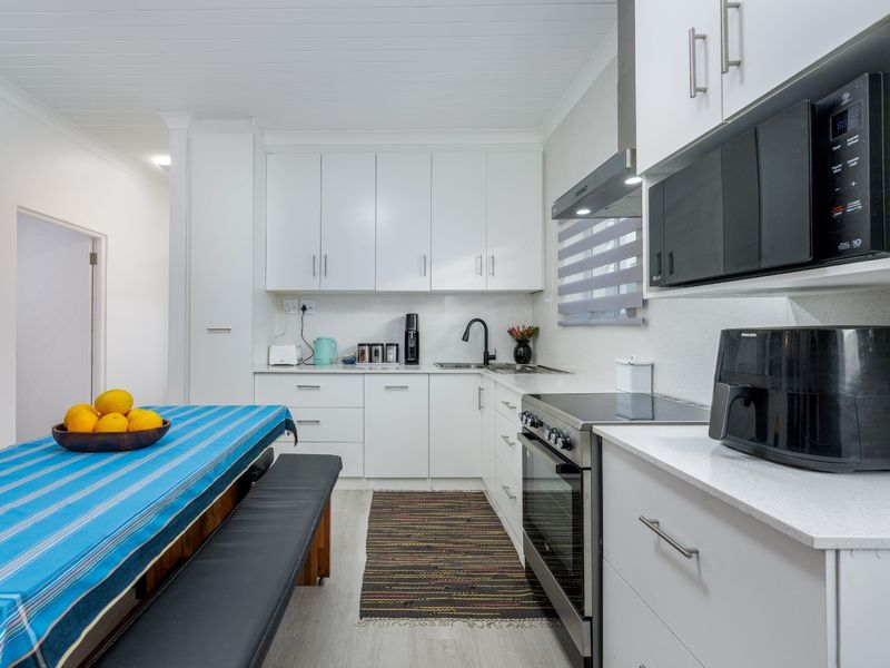 Modern kitchen featuring white cabinetry, stone countertops, integrated appliances, and a clean, functional layout with ample storage space.