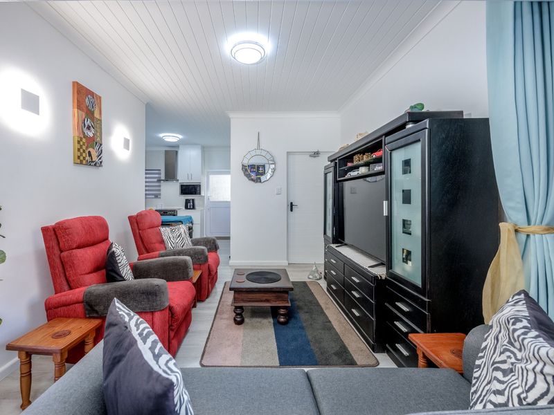 An open-plan living area featuring a tongue and groove ceiling, laminate flooring, and a view through to the functional kitchen space.