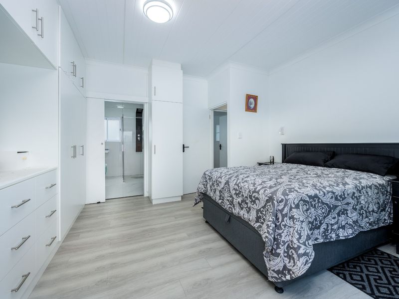 A well-maintained bedroom featuring modern laminate flooring, extensive built-in cabinetry, and direct access to an en-suite bathroom.