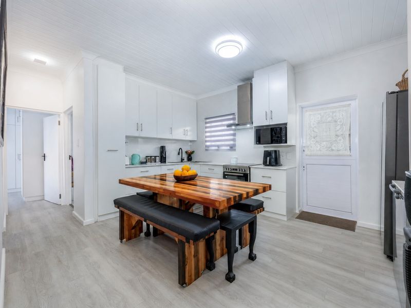 Modern kitchen featuring white cabinetry, stainless steel appliances, laminate flooring, and a tongue and groove ceiling, providing a clean and functional workspace.