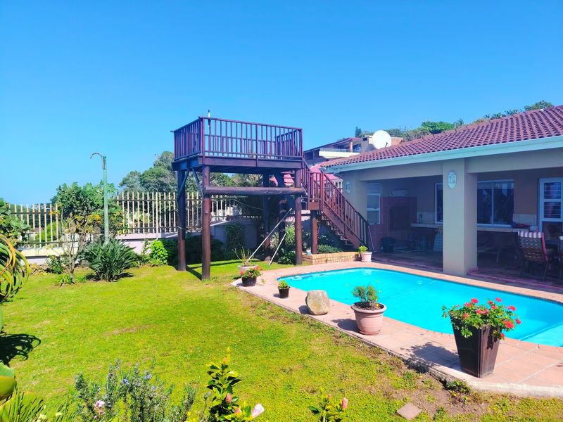 Outdoor pool area featuring a swimming pool with tiled surround, a covered patio, and a unique raised wooden viewing deck with stairs.