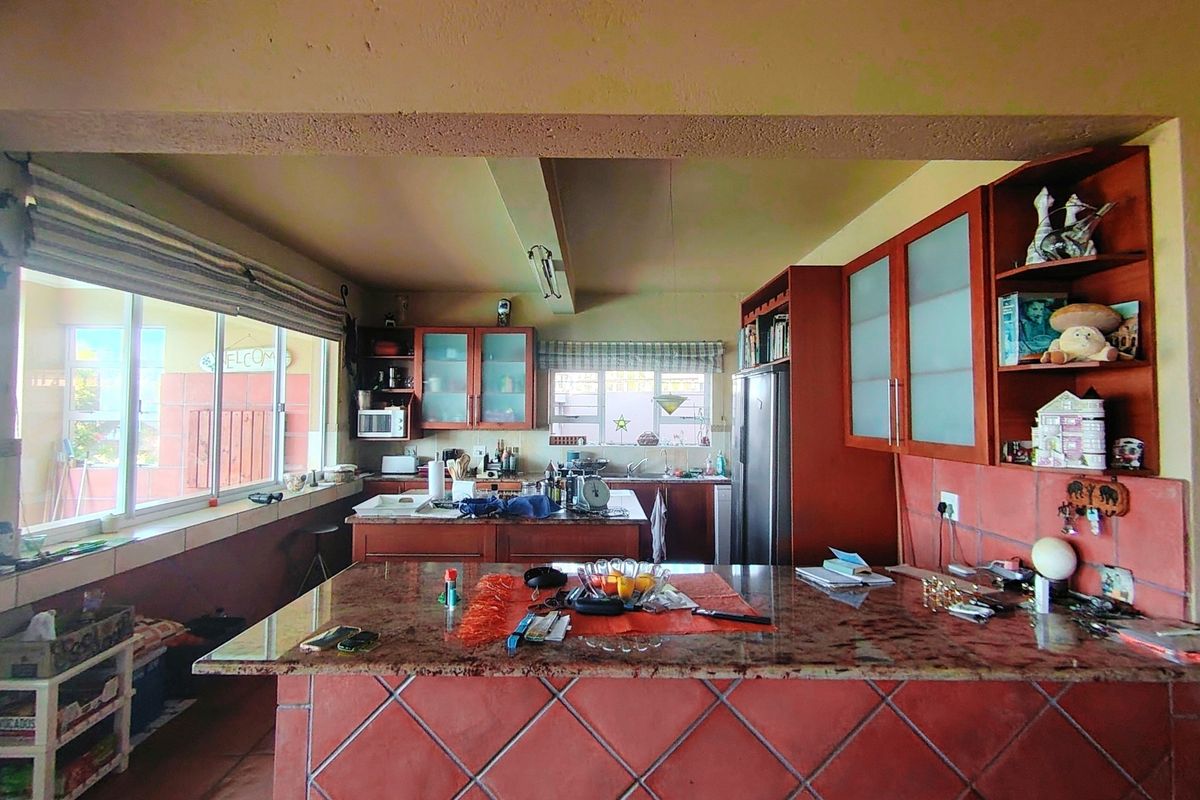 Spacious kitchen featuring a large tiled island with granite countertops, ample built-in cabinetry, and a functional layout with natural light.