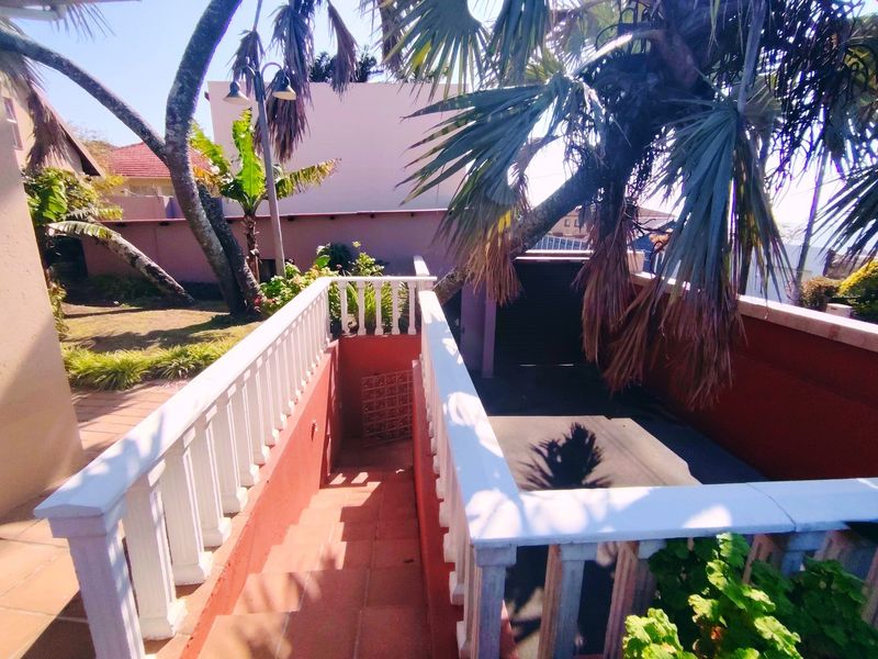 An outdoor staircase with a white balustrade leading down to a paved area in the rear garden.