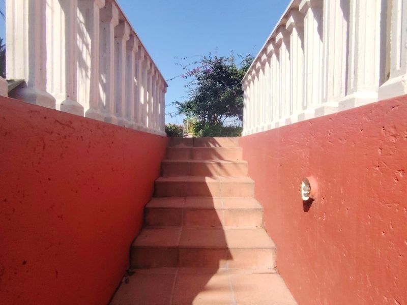An exterior staircase featuring tiled steps and concrete balustrades leading up to an elevated entrance area.
