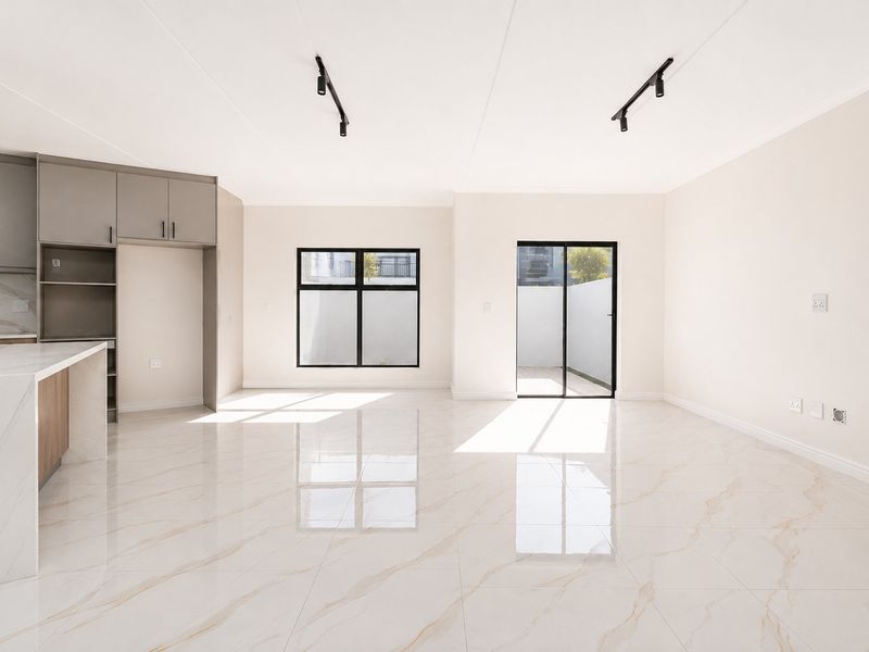 Bright and modern open-plan living area featuring high-gloss marble-look floor tiles, sleek kitchen cabinetry, and direct access to an outdoor space.