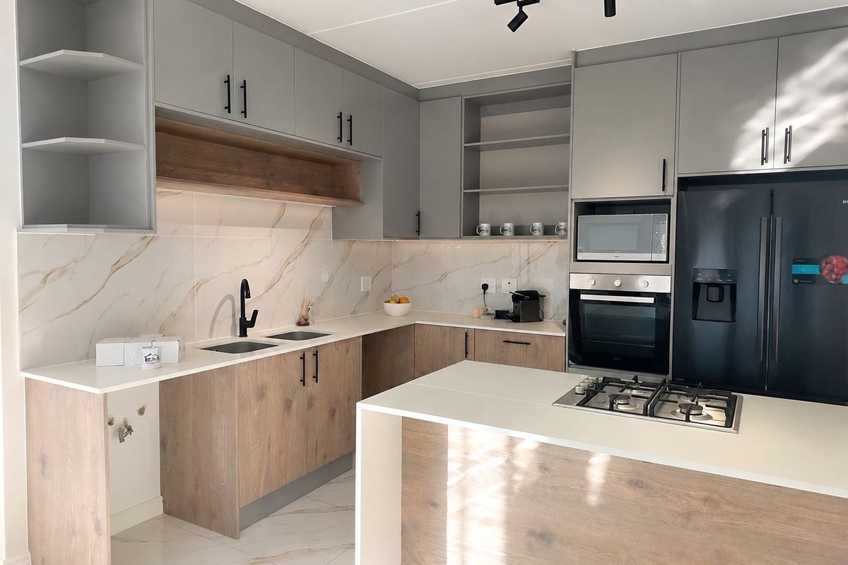 Modern kitchen featuring two-tone cabinetry, stone countertops, marble-look splashback, integrated appliances, and a central island with a gas cooktop.