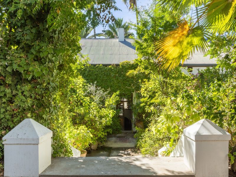 A view of the front entrance featuring a concrete staircase with masonry pillars, leading to a home with a corrugated metal roof and chimney.