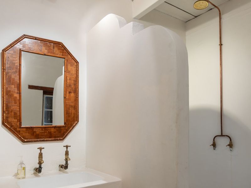 A minimalist bathroom featuring a built-in vanity and exposed copper shower plumbing with a rustic aesthetic.