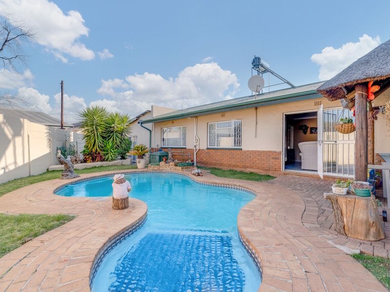 Outdoor pool area featuring a swimming pool, brick paved surround, and a thatch roof lapa, providing a functional space for outdoor relaxation.