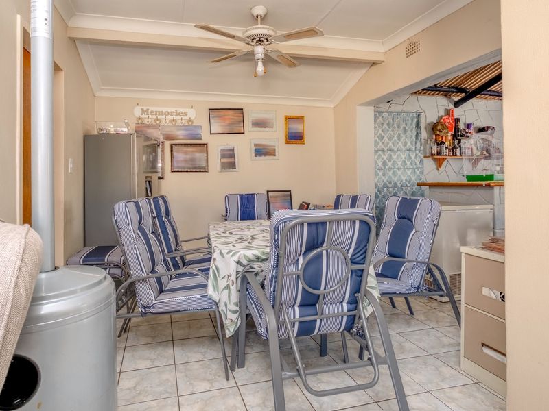 Dining area featuring tiled flooring, a ceiling fan, and a freestanding fireplace, providing a functional space for meals and gatherings.