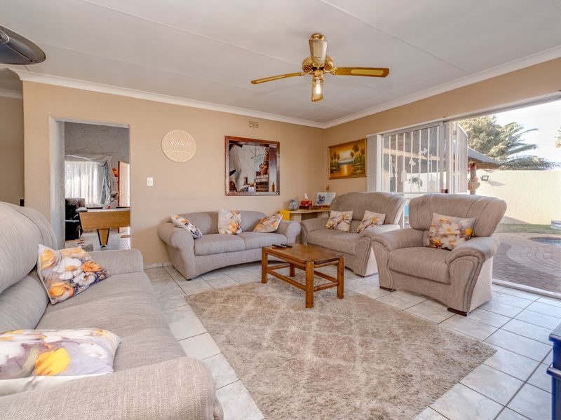 A comfortable living room featuring tiled flooring, a ceiling fan, and a sliding glass door providing direct access to the outdoor patio area.
