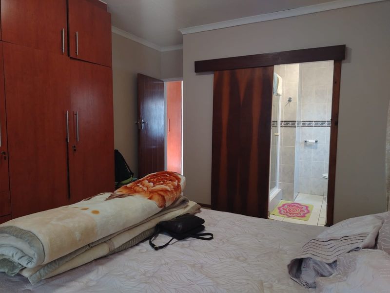 Bedroom featuring built-in wooden cupboards and a sliding door leading to an en-suite bathroom.