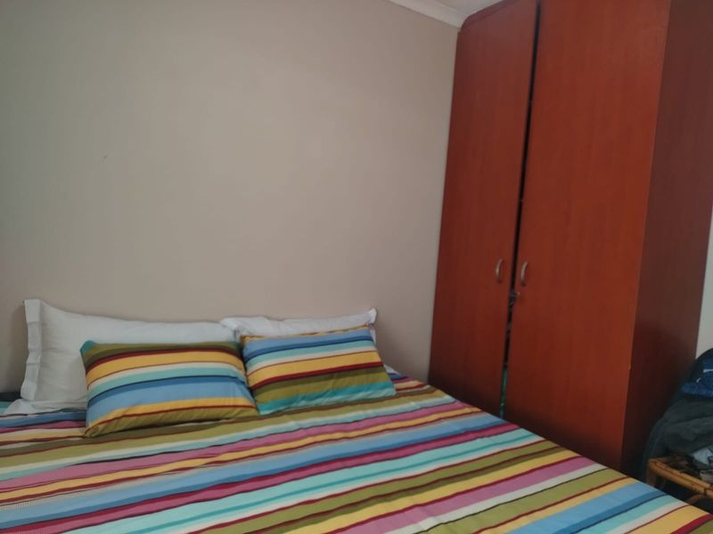 A bedroom featuring a built-in wooden wardrobe and neutral wall finishes.
