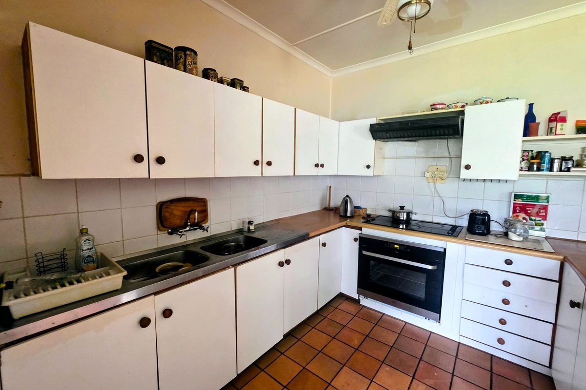 A functional kitchen featuring white cabinetry, laminate countertops, a built-in oven with electric cooktop, and tiled flooring.