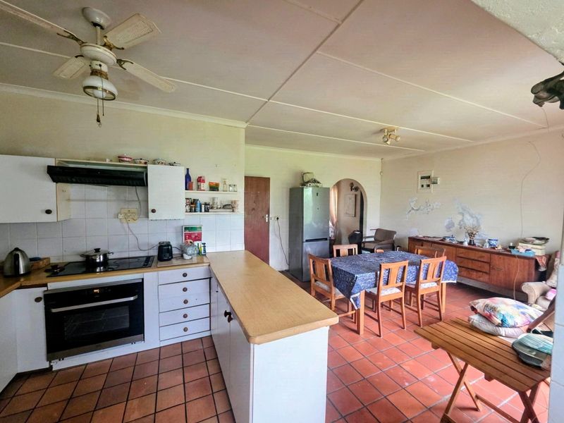 Open-plan kitchen and dining area featuring tiled flooring, built-in cabinetry, and an integrated oven, requiring cosmetic updates to the wall finishes.