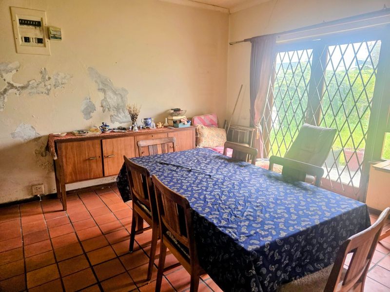 Dining room featuring terracotta floor tiles and a sliding glass door with security gate, requiring wall repairs and cosmetic updates.