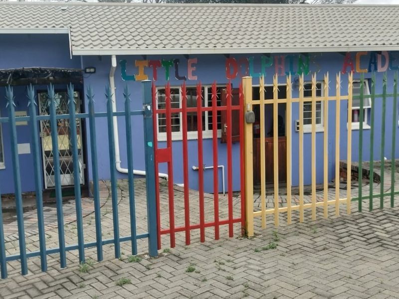Front exterior view of a commercial property featuring a paved driveway, security fencing, and a tiled roof structure.