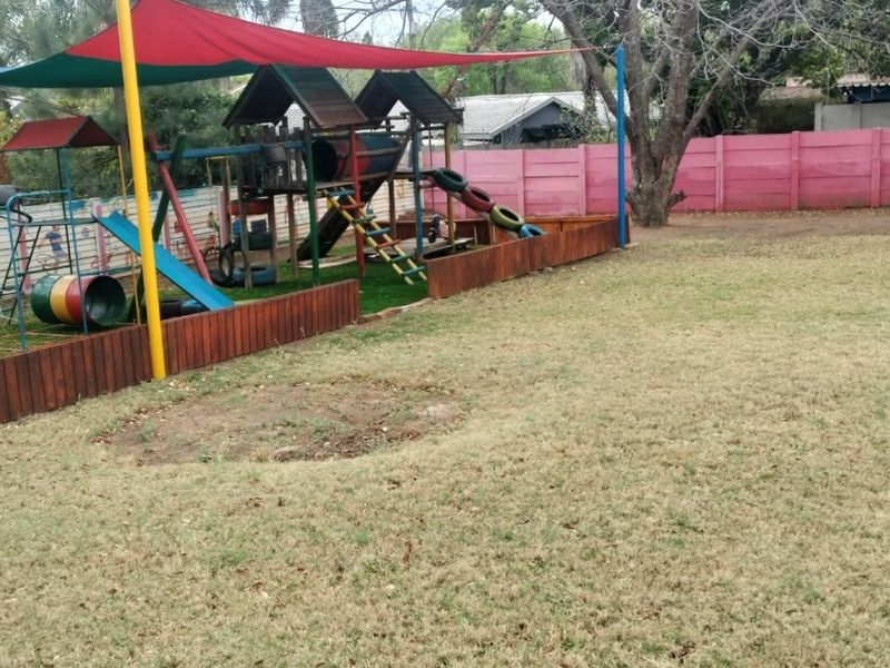 Spacious outdoor garden area featuring a dedicated play zone with shade sails, timber fencing, and perimeter walling.