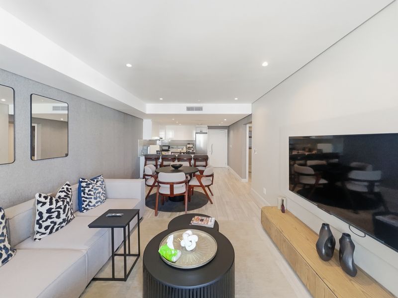 Modern open-plan living and dining area featuring sleek cabinetry, recessed lighting, ducted air conditioning, and high-quality finishes throughout.