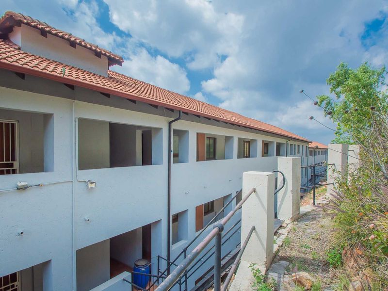 Exterior view of the apartment building rear facade featuring terracotta roofing, concrete stairwells, and metal safety railings.