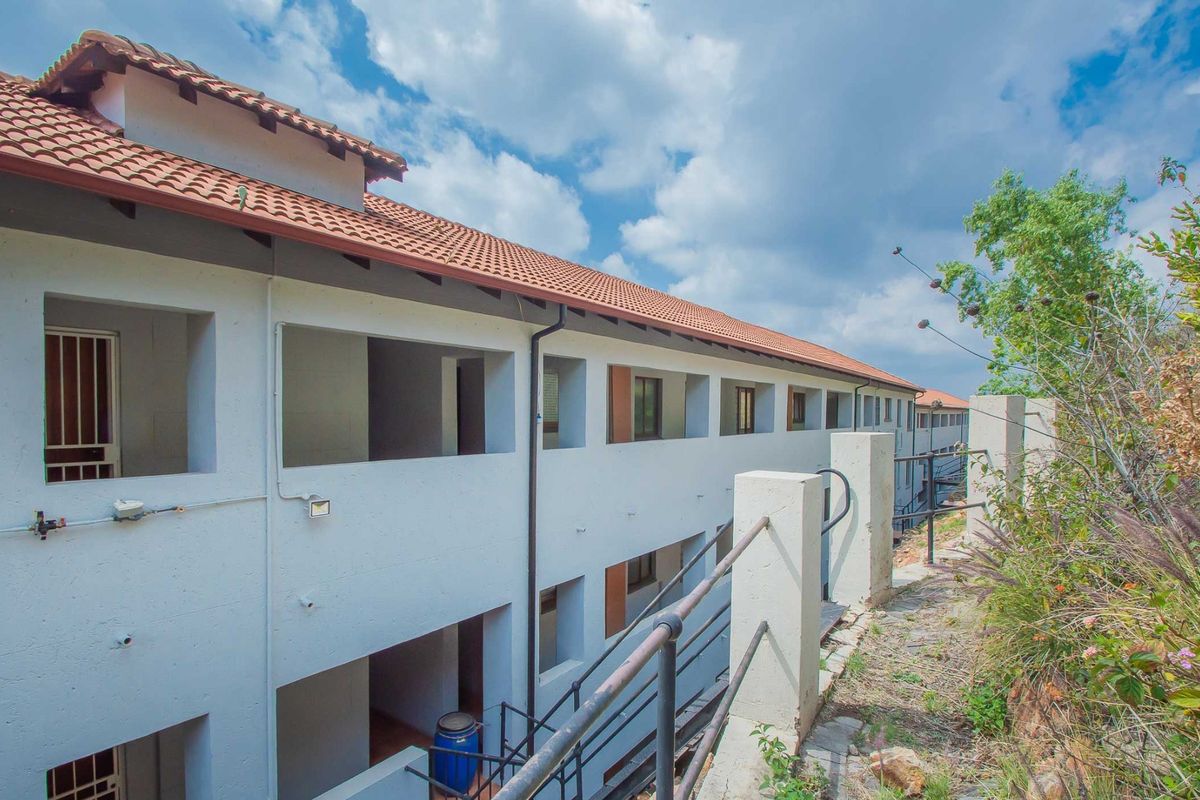 Exterior view of the apartment building rear facade featuring terracotta roofing, concrete stairwells, and metal safety railings.
