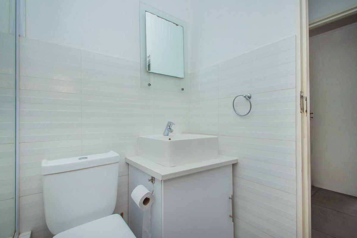 A compact bathroom featuring a modern vessel sink on a vanity cabinet, a wall-mounted mirror, and tiled wall finishes.