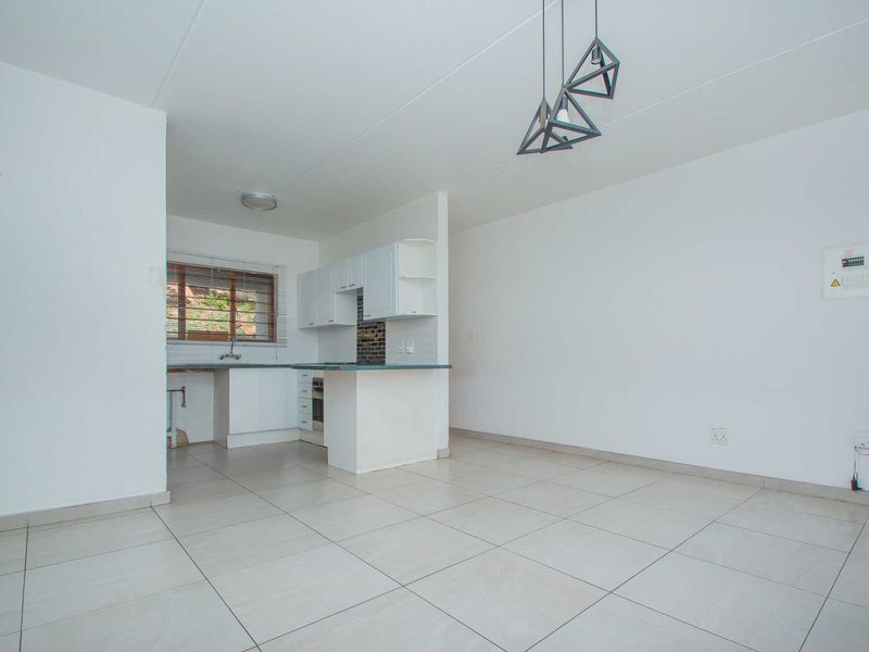 Open-plan living area featuring tiled floors and a functional kitchen with built-in cabinetry, oven, and hob.
