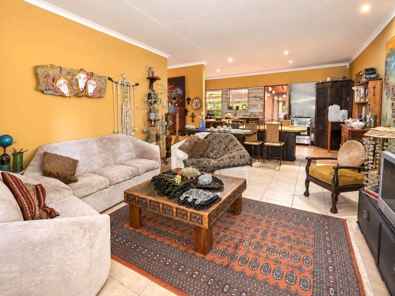 Spacious open-plan living and dining area featuring tiled flooring, recessed lighting, and a connected kitchen space with a freestanding stove.