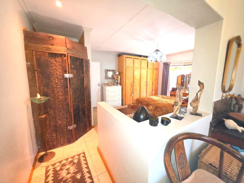 Spacious bedroom featuring built-in wooden cupboards, tiled flooring, and a partial room divider creating a distinct dressing or vanity area.