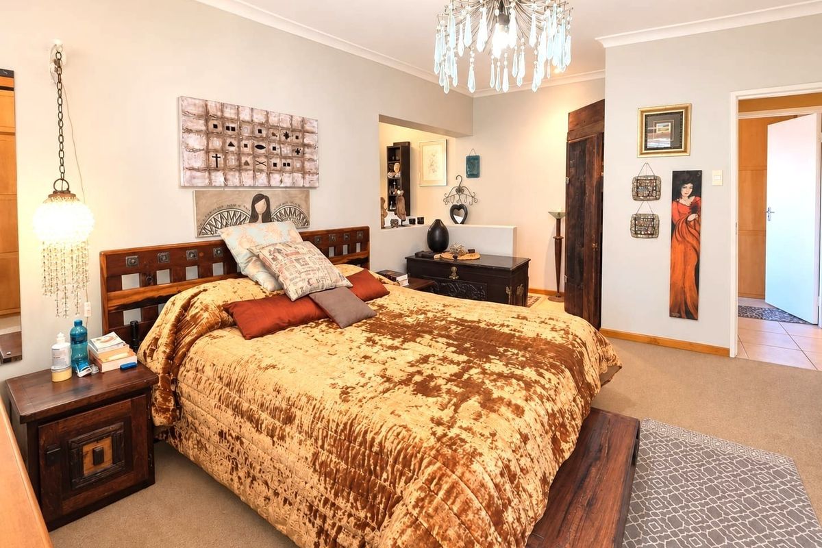 A well-maintained bedroom featuring neutral wall tones, decorative ceiling lighting, and access to an adjoining space through a doorway.