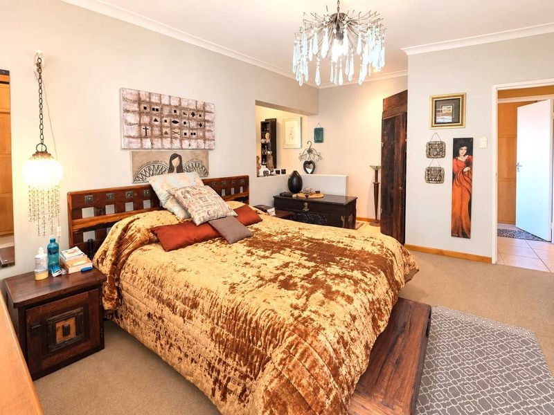 A well-maintained bedroom featuring neutral wall tones, decorative ceiling lighting, and access to an adjoining space through a doorway.
