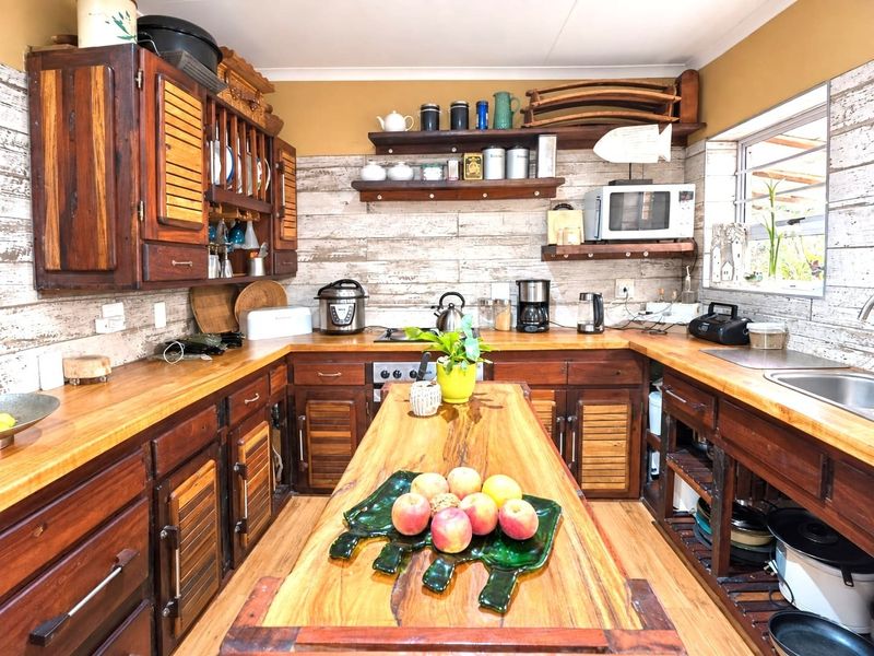 A rustic-style kitchen featuring extensive wooden cabinetry, matching wooden countertops, a central island, and a tiled backsplash with a functional layout.