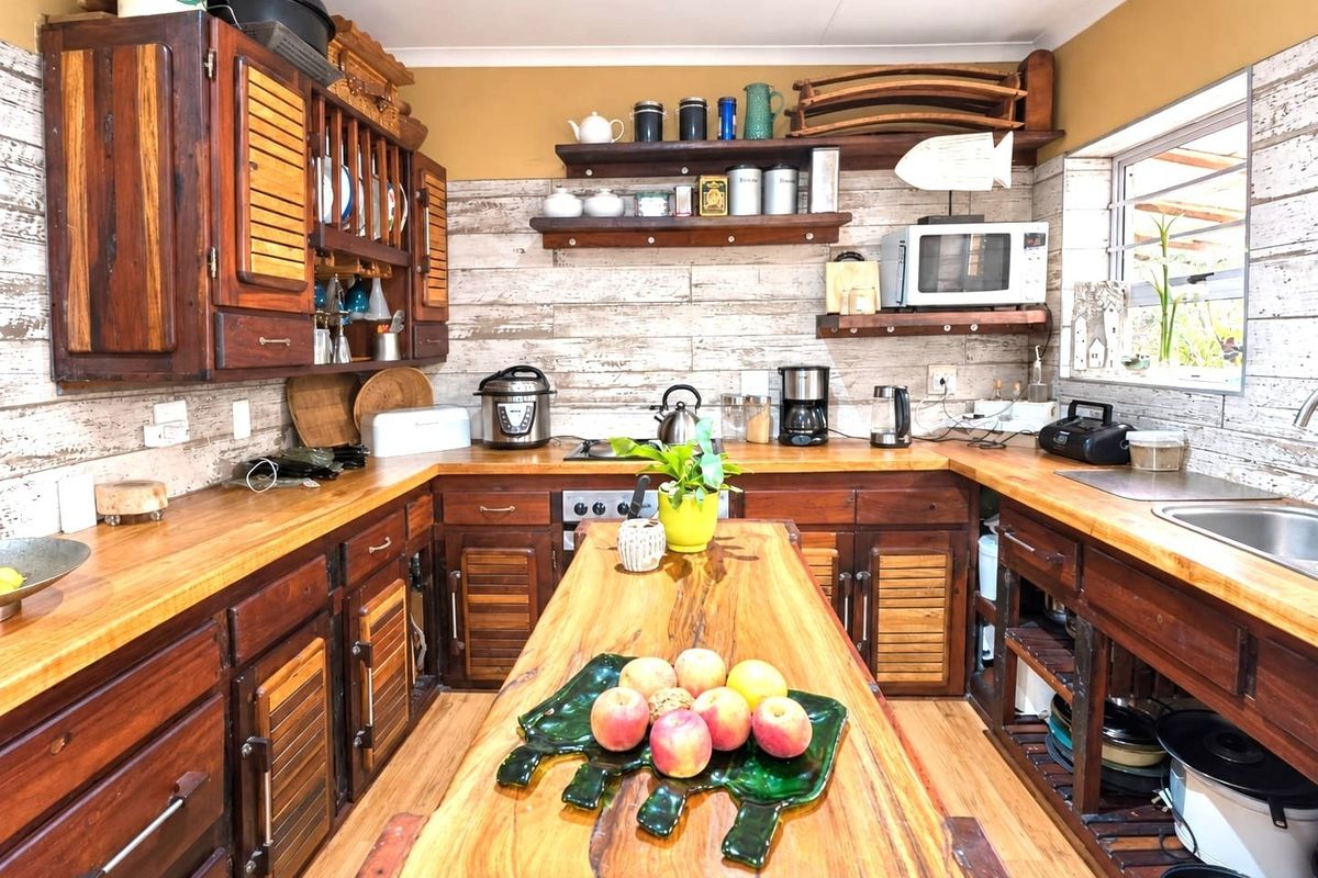 A rustic-style kitchen featuring extensive wooden cabinetry, matching wooden countertops, a central island, and a tiled backsplash with a functional layout.