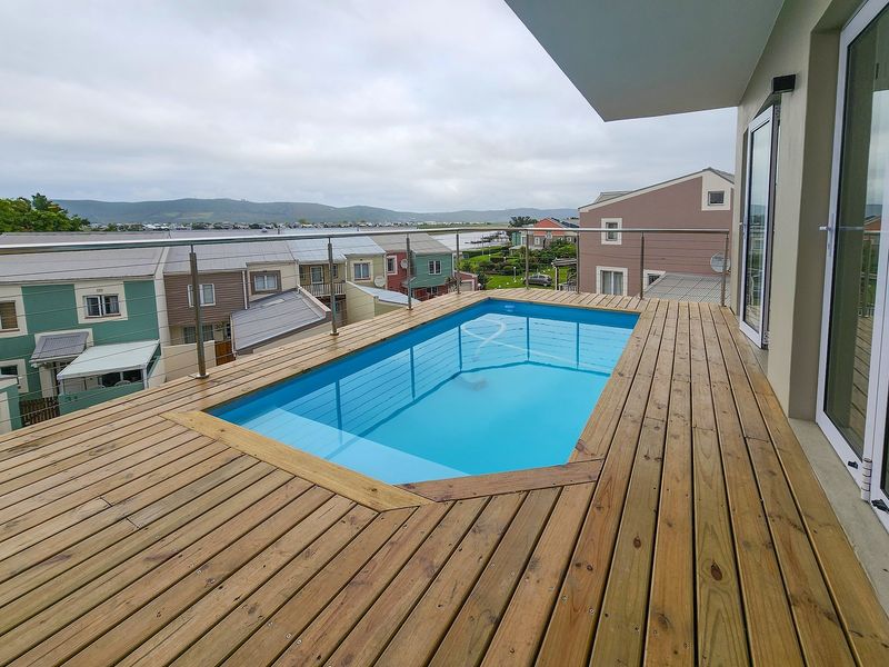 Elevated timber deck featuring a private swimming pool with modern glass balustrades, offering scenic views of the surrounding estate and landscape.