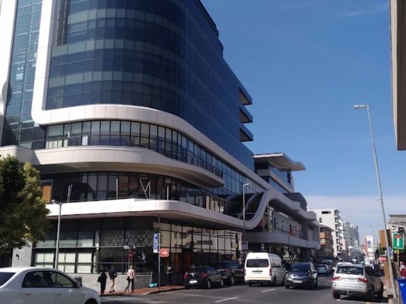 A modern multi-story office building featuring a curved glass facade and prominent street-level commercial frontage in a busy urban setting.