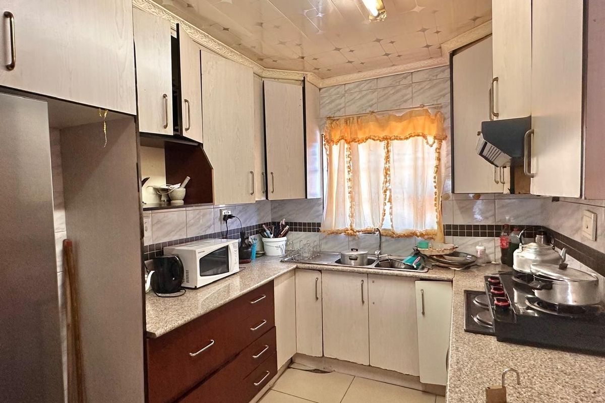 A compact kitchen featuring granite countertops, laminate cabinetry, and a tiled backsplash, offering a functional layout with potential for modern cosmetic updates.