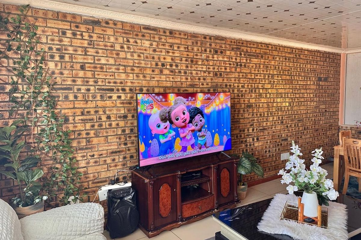 Living room featuring an exposed brick feature wall and tiled ceiling finishes.