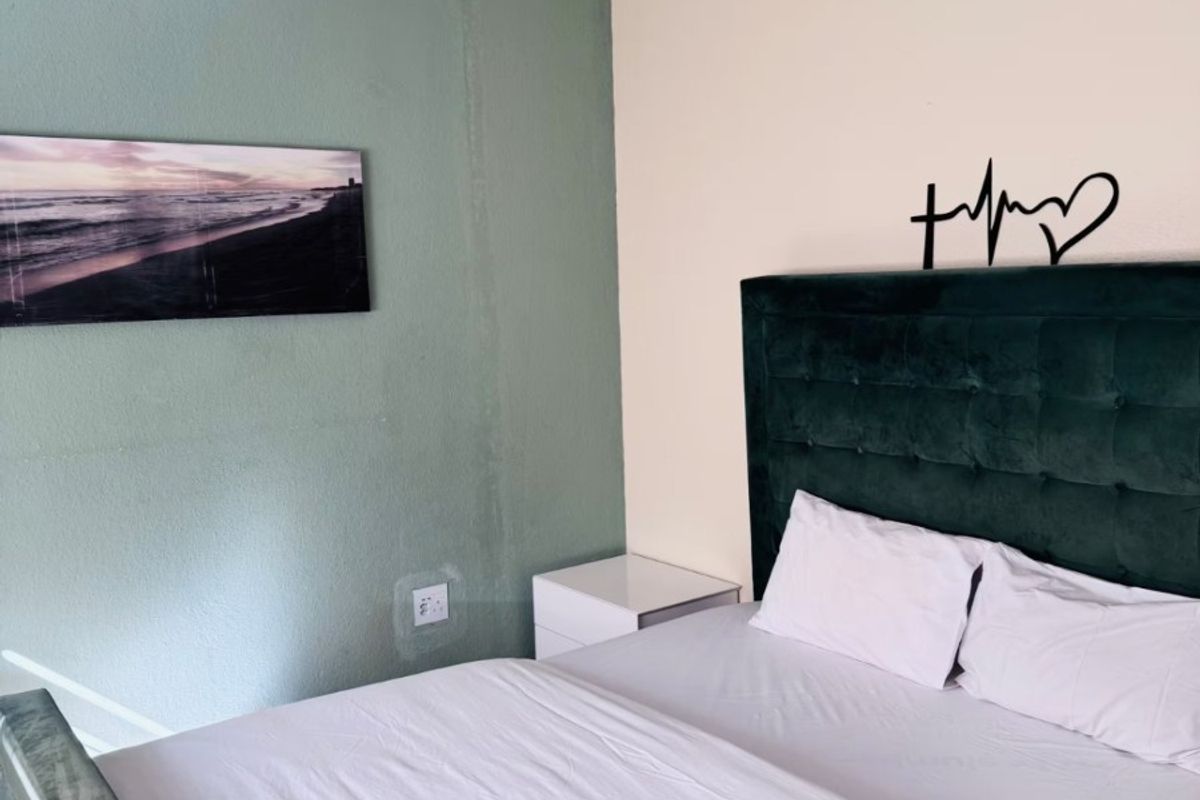A bedroom featuring a green accent wall with visible water damage, neutral wall paint, and coving.