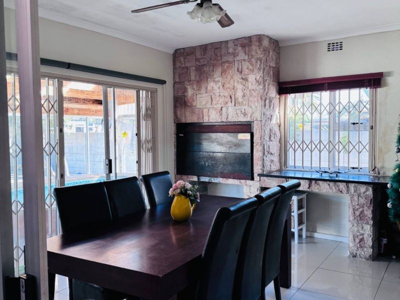 Dining room featuring a stone-clad fireplace, tiled flooring, ceiling fan, and sliding doors leading to the outdoor area.