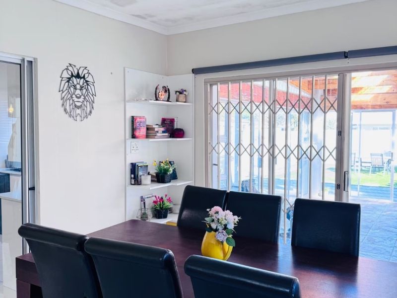Dining room featuring tiled flooring, a ceiling fan, and built-in shelving, with direct access to the outdoor patio area through a sliding glass door.